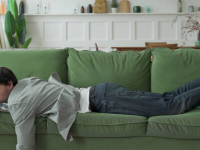 Exhausted young man came home after work flopped down on sofa.